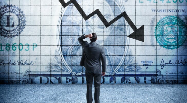 An investor looking at an arrow indicating a falling economy.