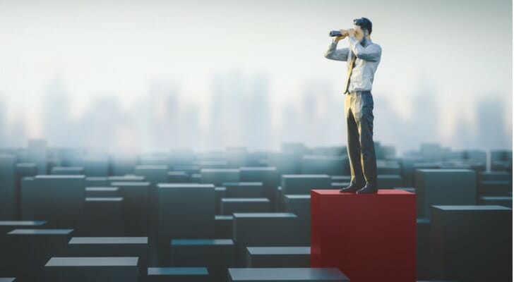 Man using a binocular, symbolizing how to spot an overvalued stock.