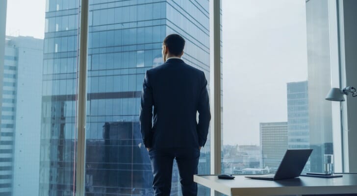 A corporate CEO looks out the window of their office.