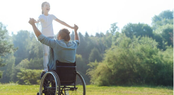 Little girl standing on the lap of her disabled father