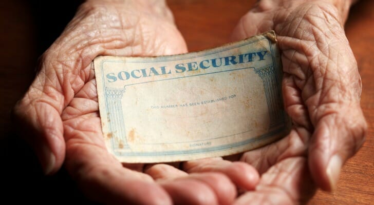 Elderly person's hands holding a Social Security card.