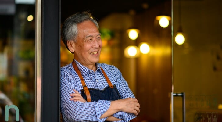 Image shows a senior employee standing in the doorway of his workplace. SmartAsset analyzed BLS data to find recent employment trends among seniors.