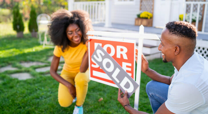 Image shows two relatively young people changing the sign outside their home from &quot;For Sale&quot; to &quot;Sold. SmartAsset found the places where more young residents are buying homes, based on 2009 and 2019 homeownership rates among residents younger than 35.