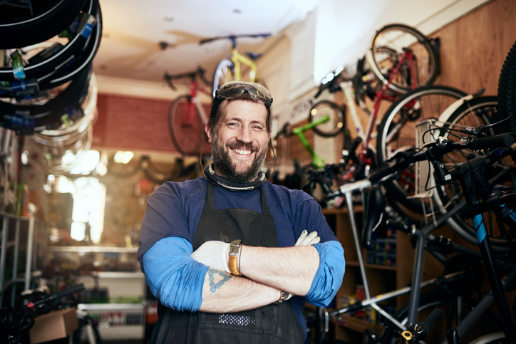 A self-employed individual poses in their bike shop.