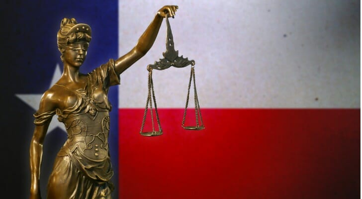 A statue holding scales in front of the Texas flag. There are few requirements for Texas premarital agreements.