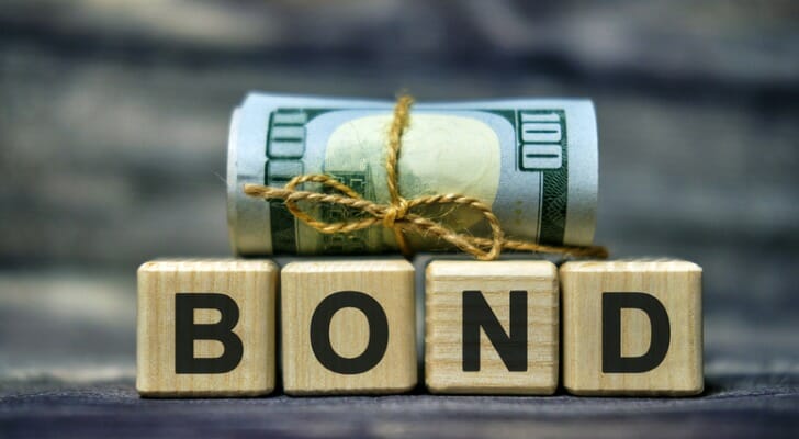 "BOND" written with block letters and a wad of bills on top of the blocks