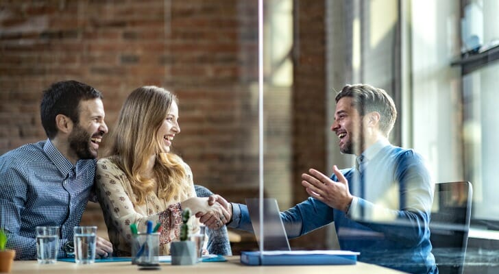 Image shows a financial advisor sitting with two clients in a business meeting. SmartAsset analyzed various data to find the top 50 fastest-growing financial advisor firms in the U.S.