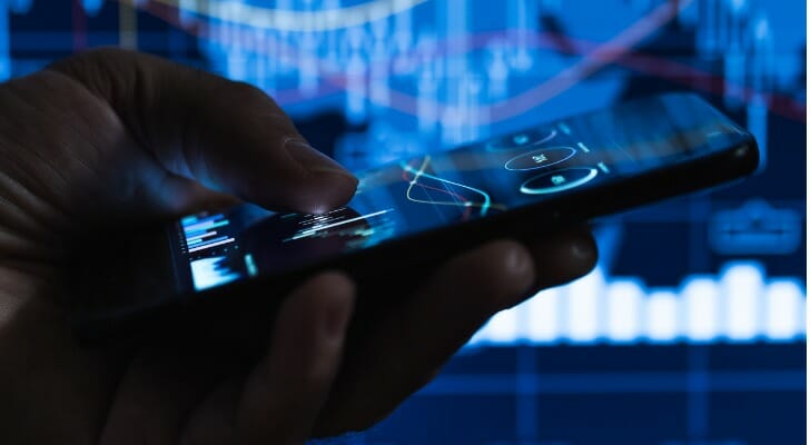 Image shows a hand holding a mobile device and checking the status of their cryptocurrency. In this article, SmartAsset takes a closer look at what Ethereum is and how to buy it.