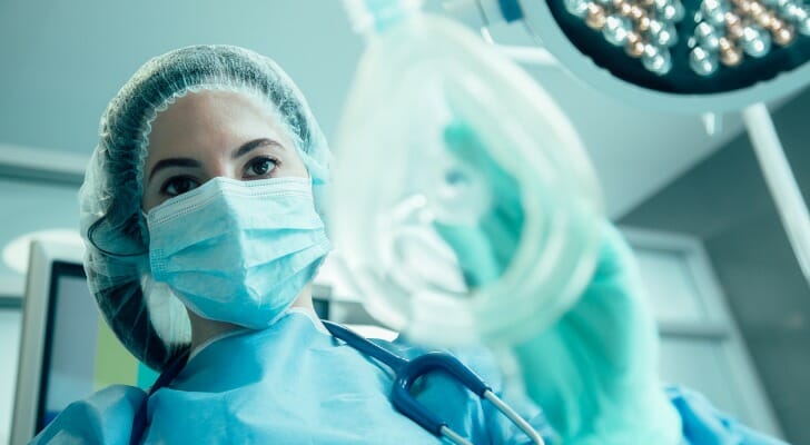 A medical professional wearing a medical uniform stands in an operating room and holds a piece of medical equipment. SmartAsset analyzed IRS and BLS data to complete its latest study on the highest-paying jobs in the U.S.