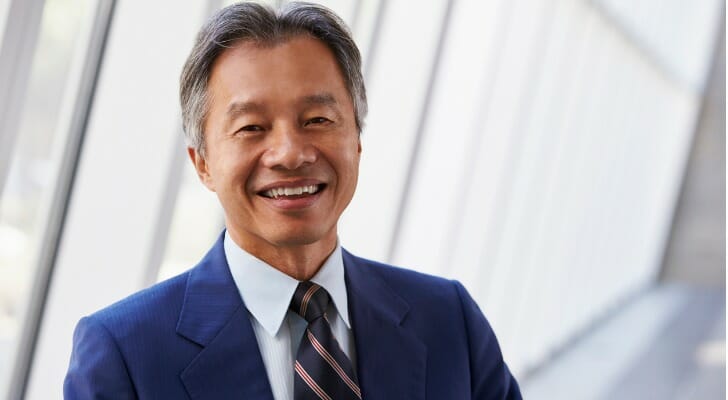 A financial advisor poses in front of the windows of an office building.
