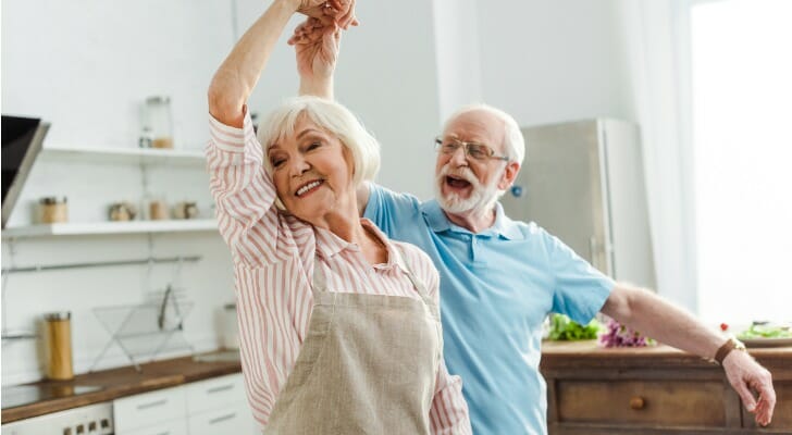 Elderly couple dancing in their kitchen, enjoying their retirement.