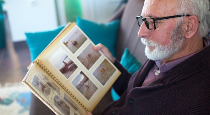 Retired man looks at family photo album