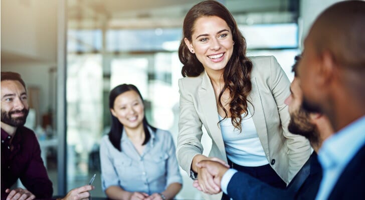 Image shows a businesswoman shaking hands with someone at a professional meeting. SmartAsset analyzed data from various sources to conduct its 2021 study on the cities with the most female six-figure earners.