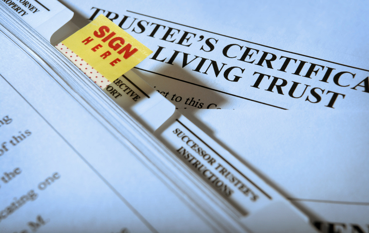 Closeup of a "Sign Here" tab on living trust documents.