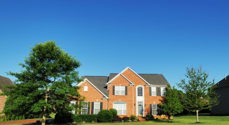 Image shows the facade of a brick home with a gray roof among some trees in its front lawn. SmartAsset analyzed various data from various sources to rank the best cities for first-time homebuyers.