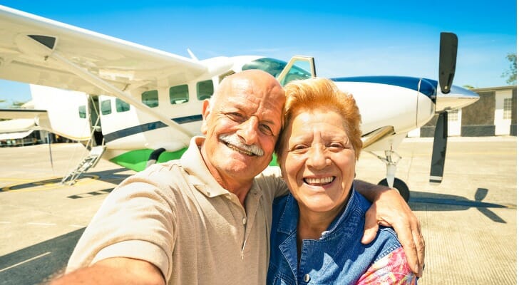 Retired couple in front of their plane, having learned how to retire with $5 million.