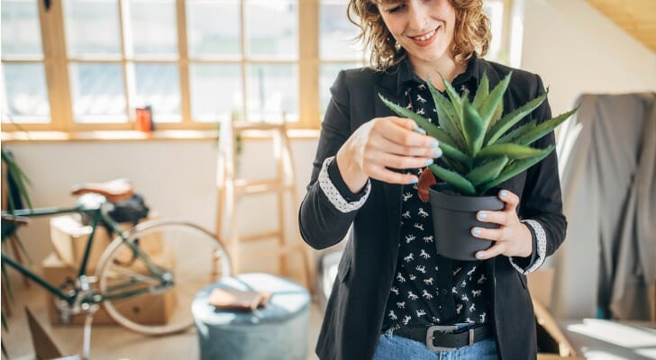 Image shows a solo renter holding a new plant to furnish the apartment that they live in. SmartAsset analyzed various data sources to conduct the 2021 edition of its study on the cities where renters can afford to live alone.
