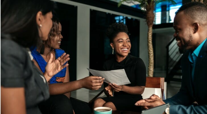 Image shows a group of professionals sitting around a coffee table and talking. SmartAsset analyzed data to identify and rank the states to which rich Gen Xers are moving.
