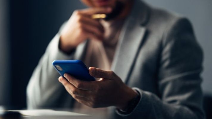 A financial advisor monitors his social media channels from his smartphone.