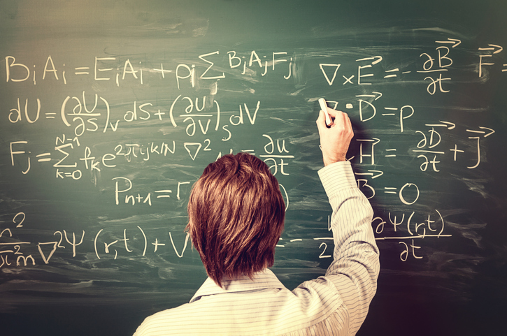 A teacher completes equations on a chalkboard.