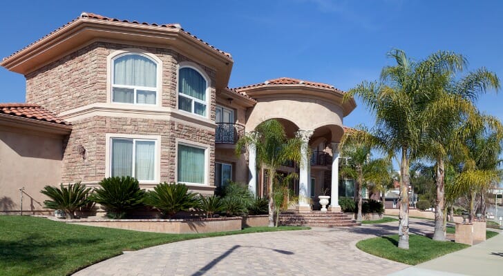 Image shows an upscale home with a paved driveway lined with palm trees. SmartAsset analyzed data from the Census Bureau to conduct their latest study on the cities with the most million-dollar homes.