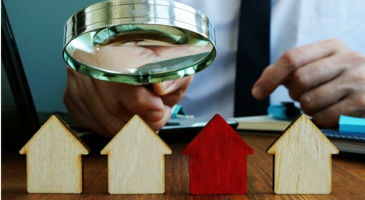 Man using a magnifying glass to inspect model houses