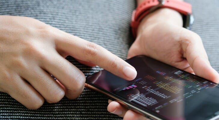 A woman looks at her cryptocurrency portfolio on her smartphone. The $1 trillion federal infrastructure bill aims to change how transactions are reported.