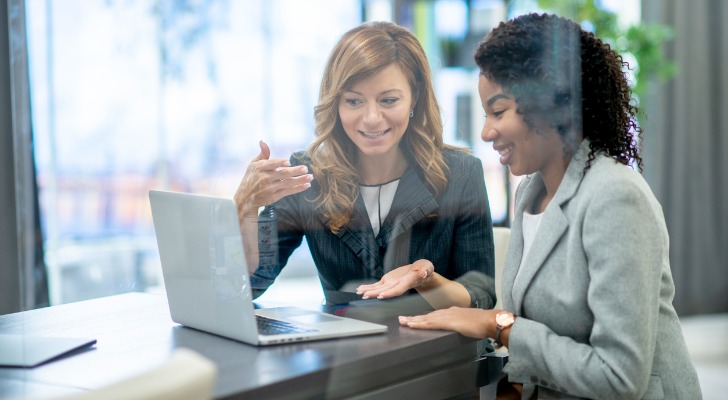 Image shows two financial advisors discussing a project at work. SmartAsset analyzed data to identify and rank the best cities for young financial advisors to start their careers.