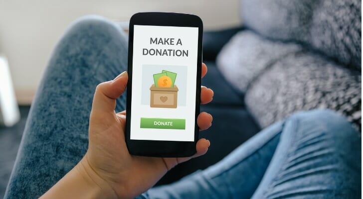 Image shows a person using their smart phone to make a donation. SmartAsset analyzed data from various sources to identify and rank the places where Americans give the most to charity.