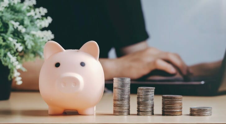 Closeup of a piggy bank next to stacks of coins.