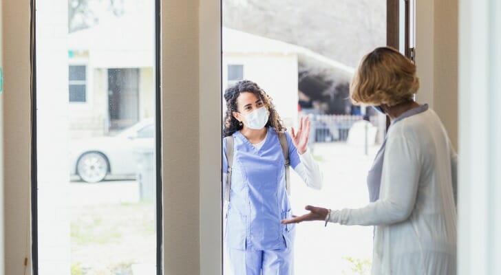 Image shows a patient opening the door of their home for a visiting nurse. Short-term care insurance may be able to help cover a cost like this.