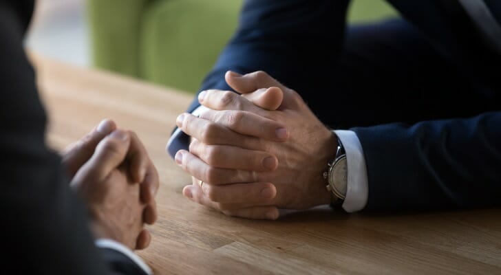 Hands of two men clasped on a table