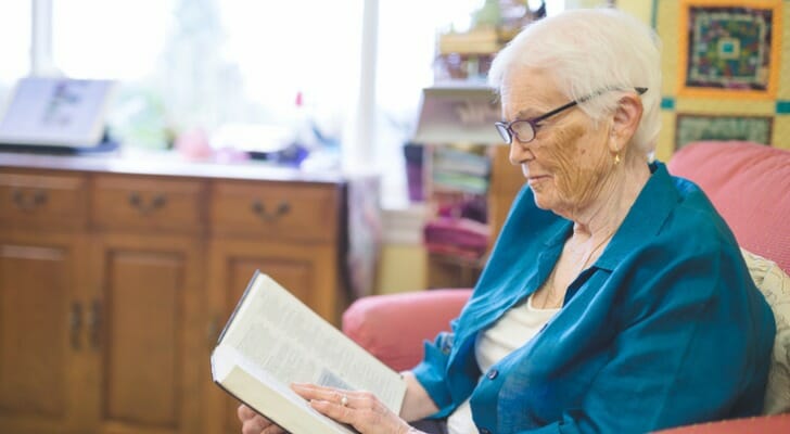 Elderly resident in a long-term care facility reading a book
