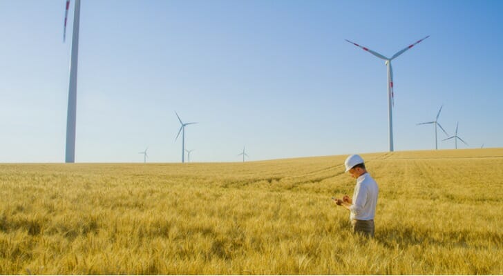 Image shows an engineer standing in a field of wind turbines. The COP26 climate change conference has put a renewed spotlight on green investments.