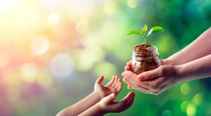 Child receiving a jar of pennies from an adult
