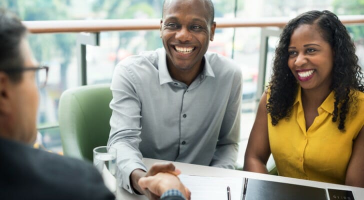 A couple meets with their financial advisor to talk about their investment portfolio. T. Rowe Price recently published its year-end tips for retirement savers.