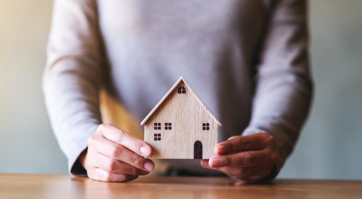 Woman holds wooden model of a house