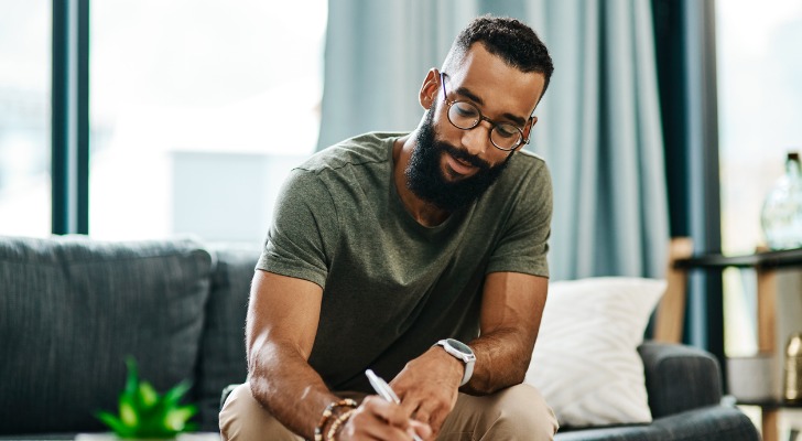 Image shows a person sitting down to write a list of questions they are preparing for a potential financial advisor.