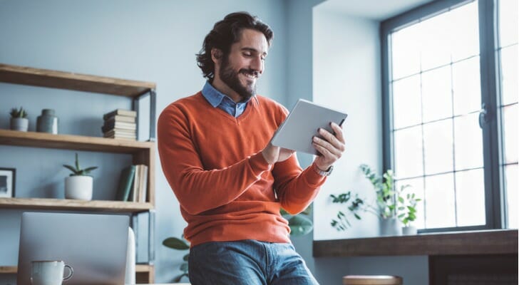 A man smiles as he looks over his dividend distributions. Vanguard announced the estimated supplemental distributions that it will pay to shareholders in March 2022.