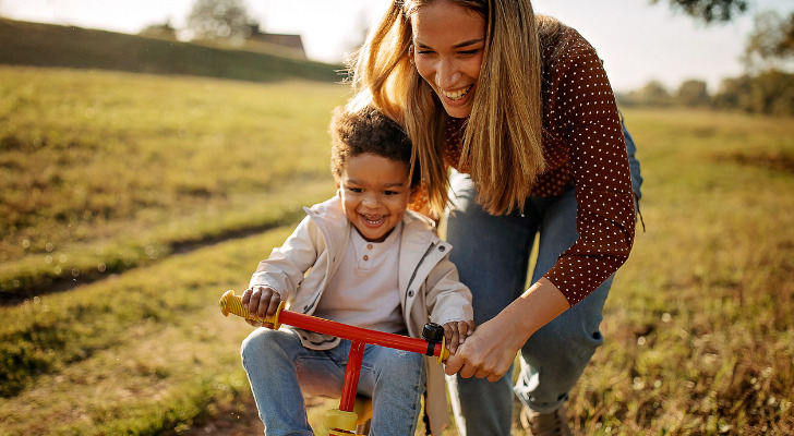 A mother playing with her son outside, having learned how to create a trust for her child.