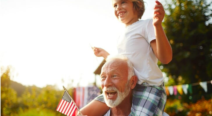 A grandfather carrying his grandchild on his shoulders.