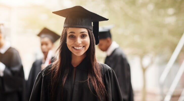 A woman smiles after receiving her college diploma. SmartAsset ranked the top cities for new college graduates in 2022.