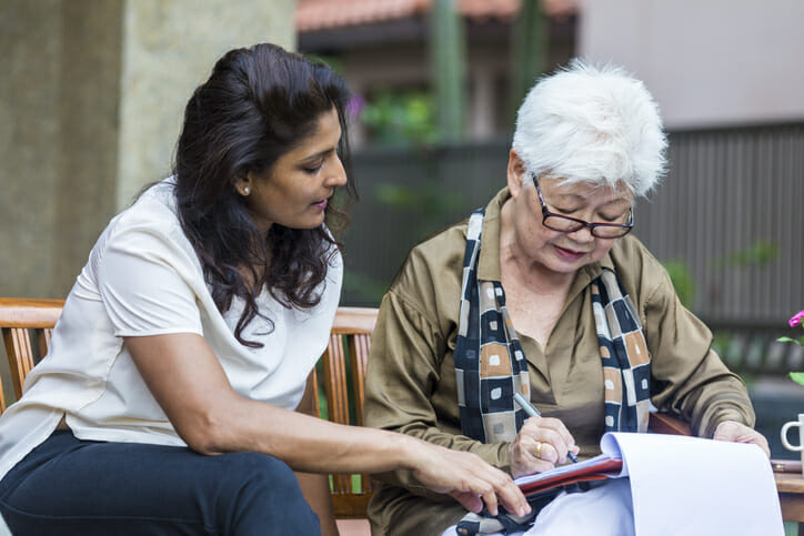 A mother and daughter fill out tax return paperwork for a living trust.
