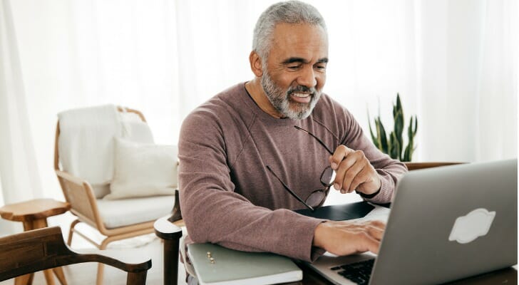 A retiree looks over his portfolio on his computer. Model portfolios using the bucket strategy have helped retirees keep their cash flowing in 2022 despite a bear market. 