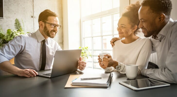 A couple discuss financial planner fees with their advisor.