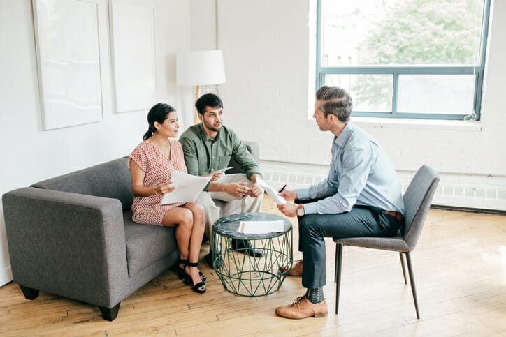 A couple meeting with a financial advisor to discuss how to invest in real estate during a recession.
