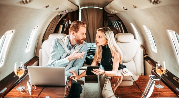 A couple on a private jet, discussing where do billionaires keep their money.