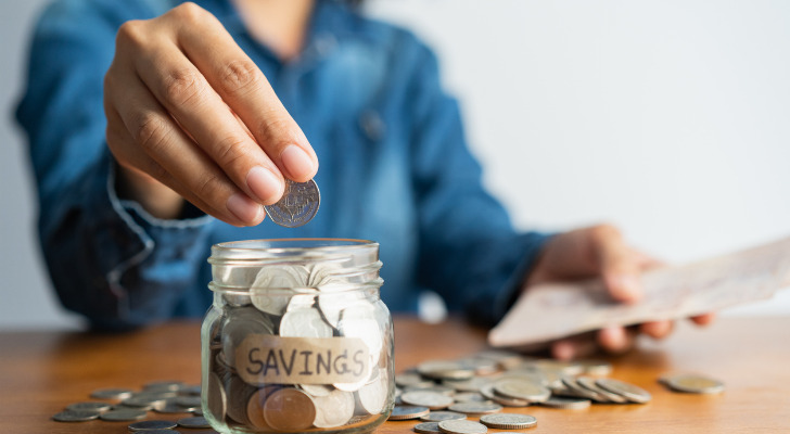 A saver putting coins in a jar labeled "savings."