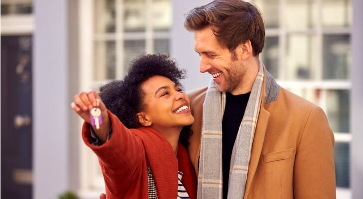 A couple with the keys to their first home, having worked with a financial advisor before buying a house.