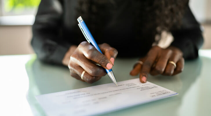 Closeup of a woman writing a check.